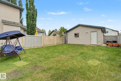 Expansive backyard featuring a detached garage with light-colored siding, a white service door, and a single window - 710 Glenwright Court, Edmonton, AB 