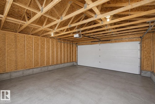 Concrete flooring with a white paneled garage door and exposed wood framing - 710 Glenwright Court, Edmonton, AB 