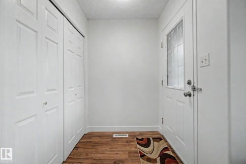 Entryway with wood-finish flooring, a white paneled door with frosted glass insert, and bi-fold closet doors - 710 Glenwright Court, Edmonton, AB 