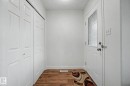 Entryway with wood-finish flooring, a white paneled door with frosted glass insert, and bi-fold closet doors - 710 Glenwright Court, Edmonton, AB 