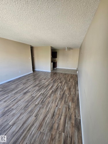 Spacious interior featuring wood-finish flooring, neutral wall paint, and a textured ceiling - 301 10615 110 Street Nw, Edmonton, AB 