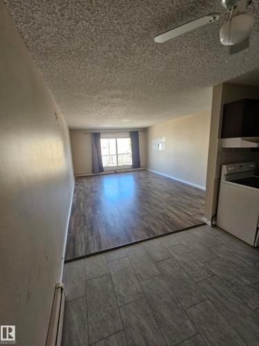 Open-concept living area featuring wood-finish flooring, a ceiling fan, and a balcony with a metal railing - 301 10615 110 Street Nw, Edmonton, AB 