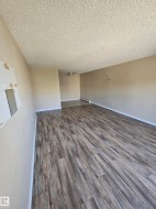 Spacious interior featuring wood-finish flooring, neutral-toned walls, and a textured ceiling - 