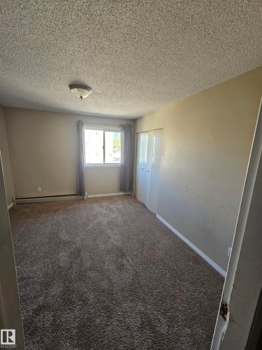 Carpeted room featuring a single window, baseboard trim, and a ceiling-mounted light fixture - 301 10615 110 Street Nw, Edmonton, AB 