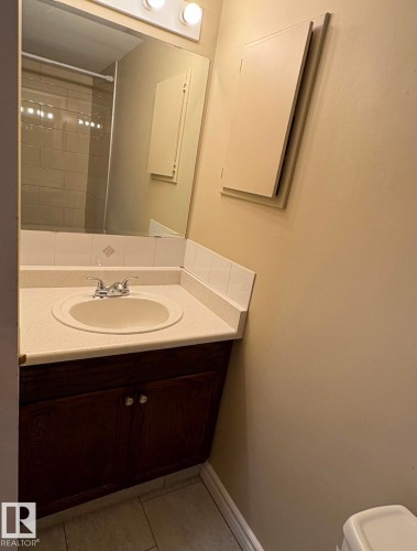 Bathroom vanity featuring a dark wood-finish cabinet with clear knobs, a white countertop with an integrated sink, and chrome faucet hardware - 301 10615 110 Street Nw, Edmonton, AB 