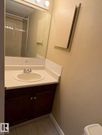 Bathroom vanity featuring a dark wood-finish cabinet with clear knobs, a white countertop with an integrated sink, and chrome faucet hardware - 