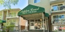 Building exterior featuring a prominent green awning with property signage, multiple levels of balconies with white railings, a light-colored siding facade, and a brick accent wall - 301 10615 110 Street Nw, Edmonton, AB 