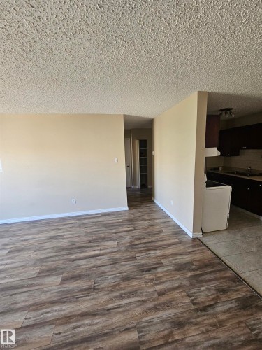 Spacious interior featuring wood-finish flooring, neutral-toned walls, and a textured ceiling - 301 10615 110 Street Nw, Edmonton, AB 