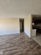 Spacious interior featuring wood-finish flooring, neutral-toned walls, and a textured ceiling - 