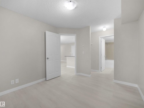 Neutral tone walls, light wood-finish flooring, and white baseboards - 220 12035 22 Avenue, Edmonton, AB 
