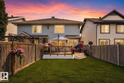 Expansive fenced backyard featuring a grassy lawn, a raised wood deck, and wood privacy fencing - 