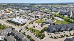 Expansive aerial view showcasing a mixed-use development with residential buildings, commercial structures, and parking areas - 