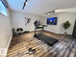 Versatile room featuring wood-finish flooring, recessed lighting, and track lighting - 