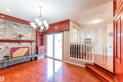 Wood-finish flooring throughout, featuring a stone-clad fireplace with a decorative mantel and hearth - 16524 116 Street, Edmonton, AB 