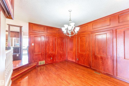 Wood-finish flooring with a paneled accent wall and crown molding - 16524 116 Street, Edmonton, AB 
