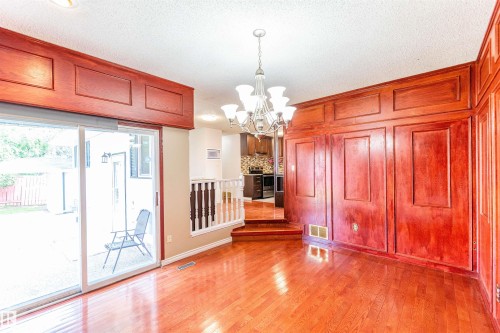 Cherry wood-finish paneling and trim, wood-finish flooring, and a sliding glass door providing outdoor access - 16524 116 Street, Edmonton, AB 