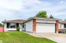 Single-story residence featuring a two-car garage with a white sectional door, brick accents, and white siding - 16524 116 Street, Edmonton, AB 
