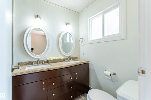 Bathroom vanity featuring a dual sink design with individual oval mirrors - 16524 116 Street, Edmonton, AB 