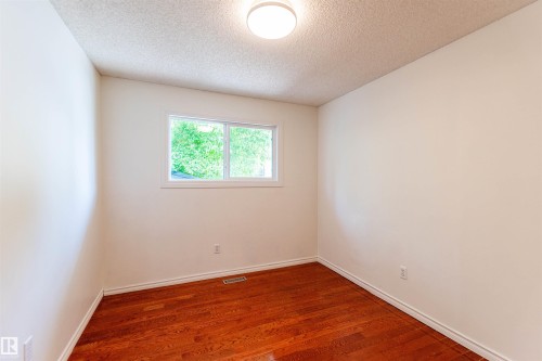 Bright room featuring wood-finish flooring, white walls, and a white trim baseboard - 16524 116 Street, Edmonton, AB 