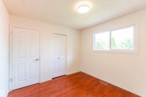 Room featuring wood-finish flooring, a double-paned window, a flush mount ceiling light, a six-panel door, and a bi-fold closet door - 16524 116 Street, Edmonton, AB 