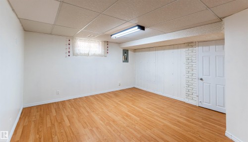 Spacious room featuring wood-finish flooring, white walls, and a drop ceiling with recessed lighting - 16524 116 Street, Edmonton, AB 