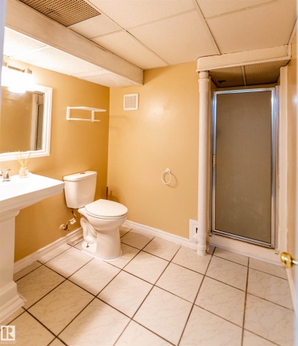 Bathroom featuring a pedestal sink, white toilet, and a glass-enclosed shower - 16524 116 Street, Edmonton, AB 