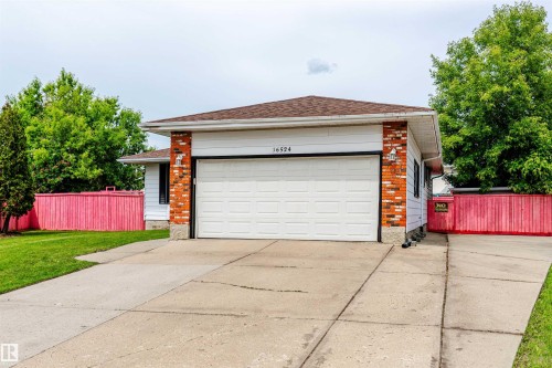 Exterior residence featuring a prominent white garage door, brick accents, and white siding - 16524 116 Street, Edmonton, AB 
