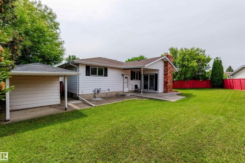 Expansive green lawn with a white horizontal siding home and a red privacy fence - 16524 116 Street, Edmonton, AB 
