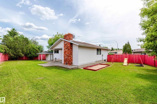 Expansive grassy lawn with a red perimeter fence - 16524 116 Street, Edmonton, AB 