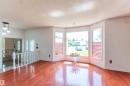 Bay window with three panes, featuring wood-finish flooring and a white spindle railing - 16524 116 Street, Edmonton, AB 
