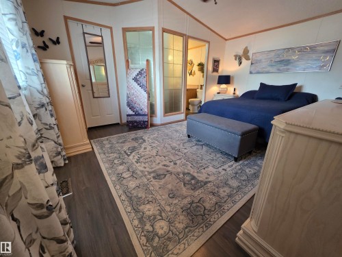 Spacious bedroom featuring wood-finish flooring, a ceiling fan, and decorative wall paneling - 88B 3400 48 Street, Stony Plain, AB 