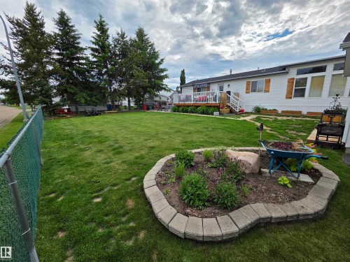 Expansive lawn with a chain-link fence and mature evergreen trees - 88B 3400 48 Street, Stony Plain, AB 