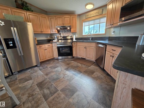Kitchen featuring light wood cabinetry, dark countertops, and stainless steel appliances - 88B 3400 48 Street, Stony Plain, AB 