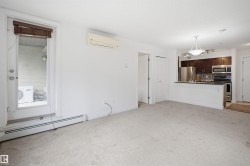 Open-concept living area featuring light-colored carpeting, a wall-mounted mini-split HVAC unit, and baseboard heating - 