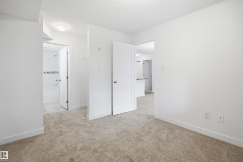 Neutral-toned carpet flooring extends throughout the room, complemented by crisp white walls and baseboards - 115 274 Mcconachie Drive, Edmonton, AB 