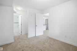 Neutral-toned carpet flooring extends throughout the room, complemented by crisp white walls and baseboards - 