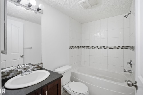 Bathroom featuring a dark wood-finish vanity with a white oval sink, chrome faucet, and dark countertop - 115 274 Mcconachie Drive, Edmonton, AB 
