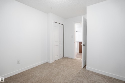 Carpeted room with white walls, white baseboards, and a bi-fold closet door - 115 274 Mcconachie Drive, Edmonton, AB 