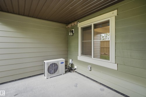Covered patio area featuring concrete flooring, a single window with white trim, and a wall-mounted exterior light fixture - 115 274 Mcconachie Drive, Edmonton, AB 