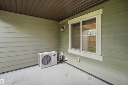 Covered patio area featuring concrete flooring, a single window with white trim, and a wall-mounted exterior light fixture - 