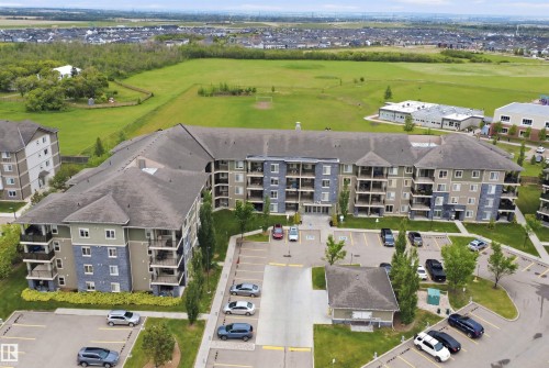Multi-story residential building featuring balconies and a large parking area - 115 274 Mcconachie Drive, Edmonton, AB 