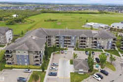 Multi-story residential building featuring balconies and a large parking area - 