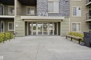 Building exterior featuring a stone facade accent, horizontal siding, and multiple balconies with dark railings - 115 274 Mcconachie Drive, Edmonton, AB 