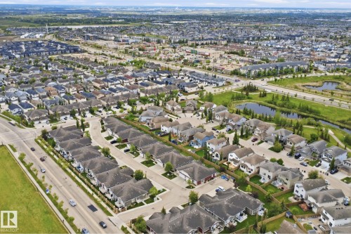 Aerial perspective of a developed residential area featuring various single-family homes and townhomes with dark shingle roofs - 115 274 Mcconachie Drive, Edmonton, AB 