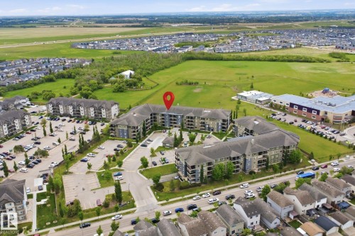 Multi-story residential complex with ample surface parking, surrounded by green spaces - 115 274 Mcconachie Drive, Edmonton, AB 