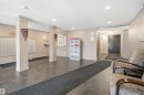 Building lobby featuring grey tile flooring, recessed ceiling lighting, and a mail area with individual boxes and parcel lockers - 115 274 Mcconachie Drive, Edmonton, AB 