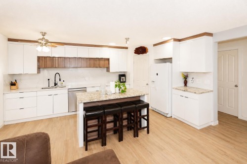 Modern kitchen featuring wood-finish flooring, white cabinetry, and light-toned countertops - 8523 7 Avenue Sw, Edmonton, AB 