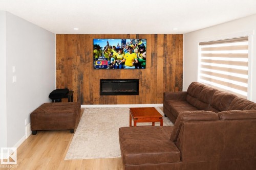 Feature wall with wood-finish paneling and an integrated electric fireplace - 8523 7 Avenue Sw, Edmonton, AB 