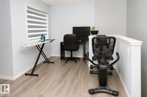Loft area featuring light wood-finish flooring, a contemporary window treatment, and a knee wall with a white cap - 8523 7 Avenue Sw, Edmonton, AB 