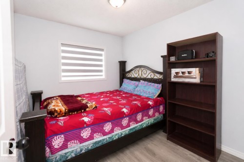 Spacious room featuring light gray walls, wood-finish flooring, and a single window with horizontal blinds - 8523 7 Avenue Sw, Edmonton, AB 